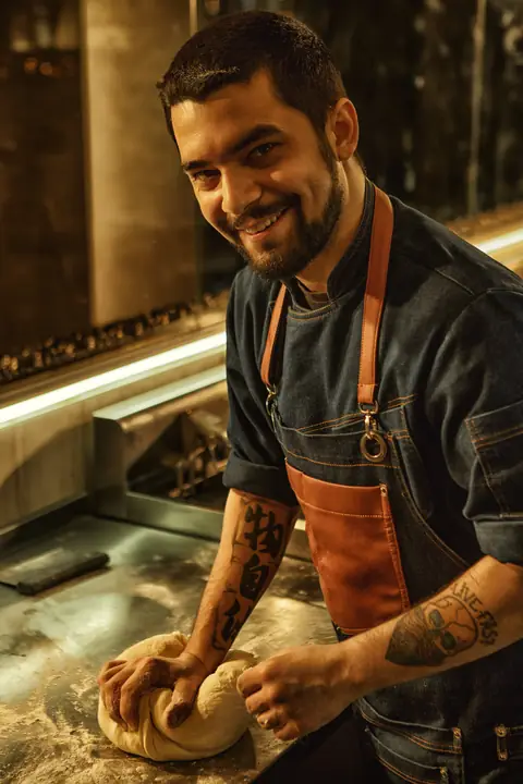 Il pizzaiolo sorride mentre lavora un panetto